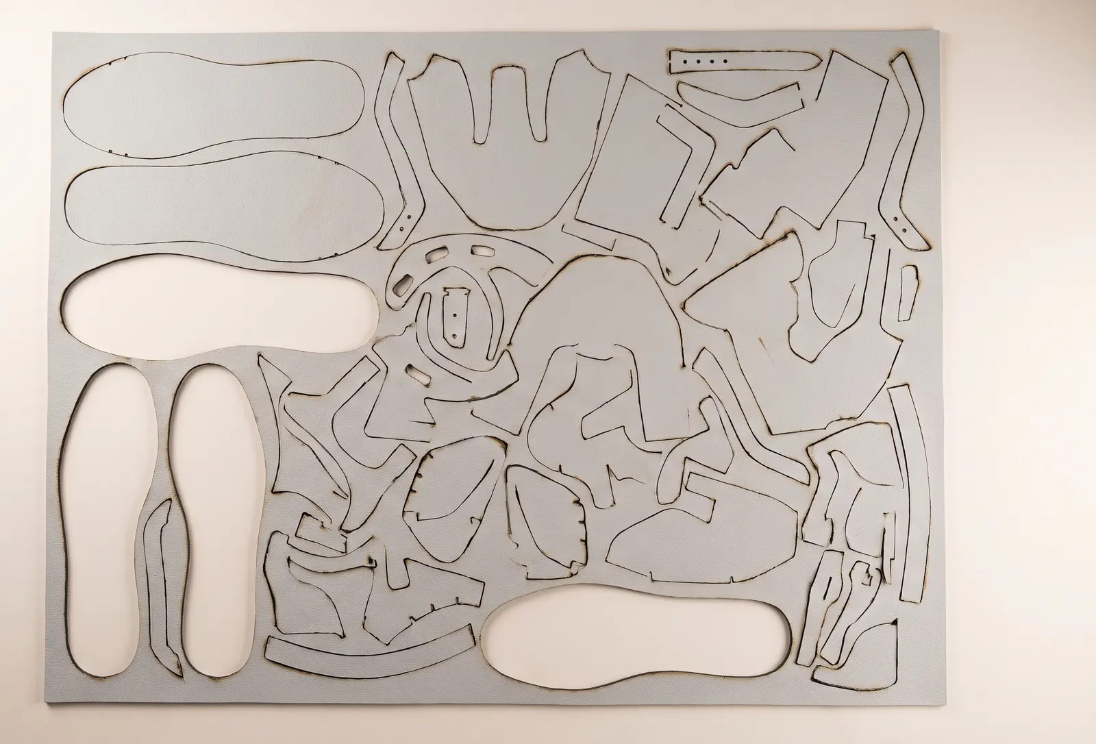 A laser-cut material sheet with tightly nested pattern pieces.