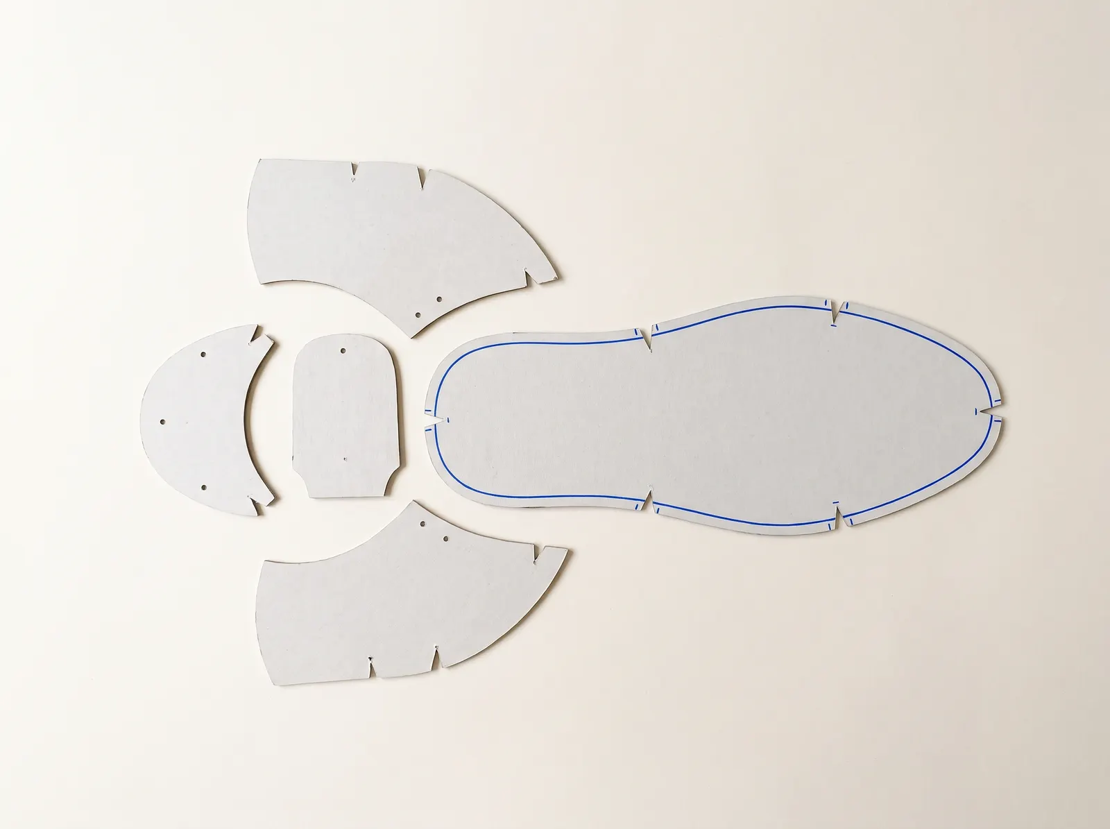 Cardboard shoe pattern pieces; one outline retraced in blue.